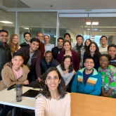 The first cohort of DEDP master's students stand with J-PAL and DEDP faculty directors Abhijit Banerjee, Esther Duflo, and Benjamin Olken in an MIT classroom.